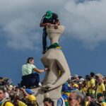 Manifestante picha a estátua da Justiça, na praça dos Três Poderes, no dia 8 de janeiro de 2023