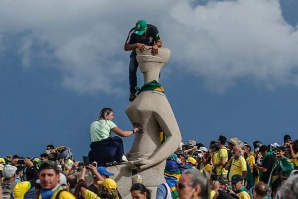 Manifestante picha a estátua da Justiça, na praça dos Três Poderes, no dia 8 de janeiro de 2023