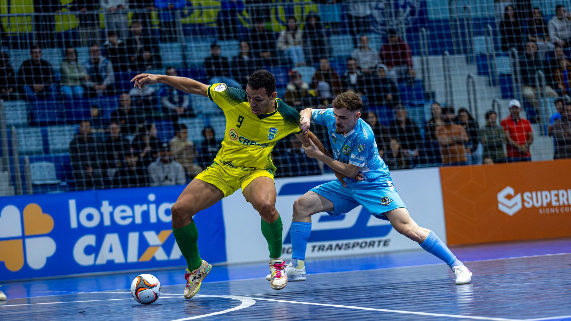 Jogadores do Associação Sorriso de Futsal e Fazenda Futsal disputando a posse de bola.